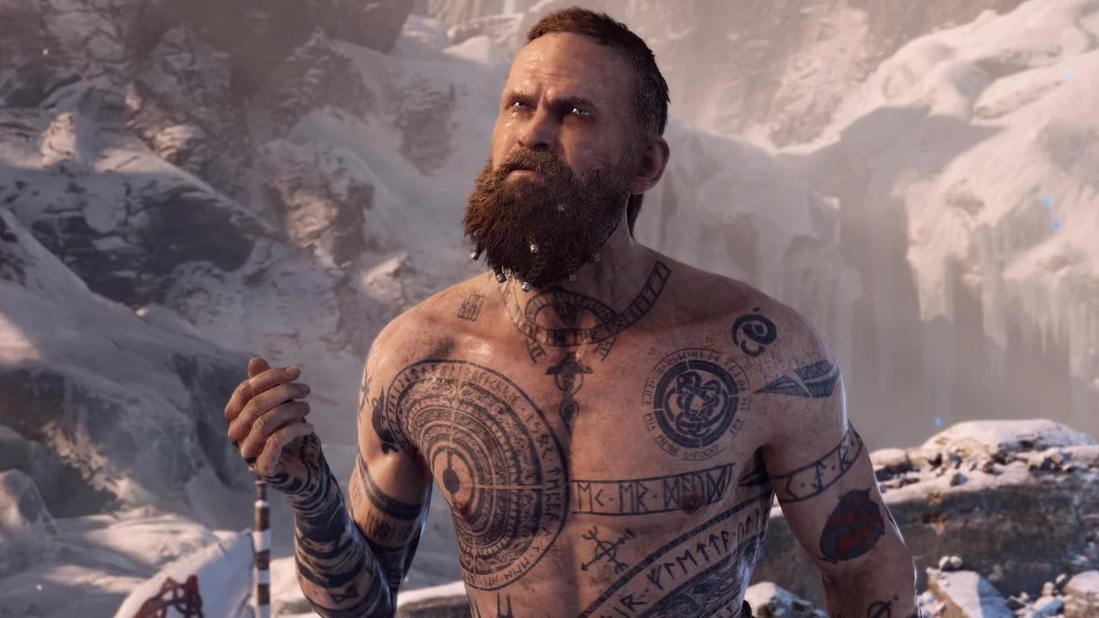 Baldur as depicted in God of War (2018), tattooed and bearded, standing in a snowy landscape.